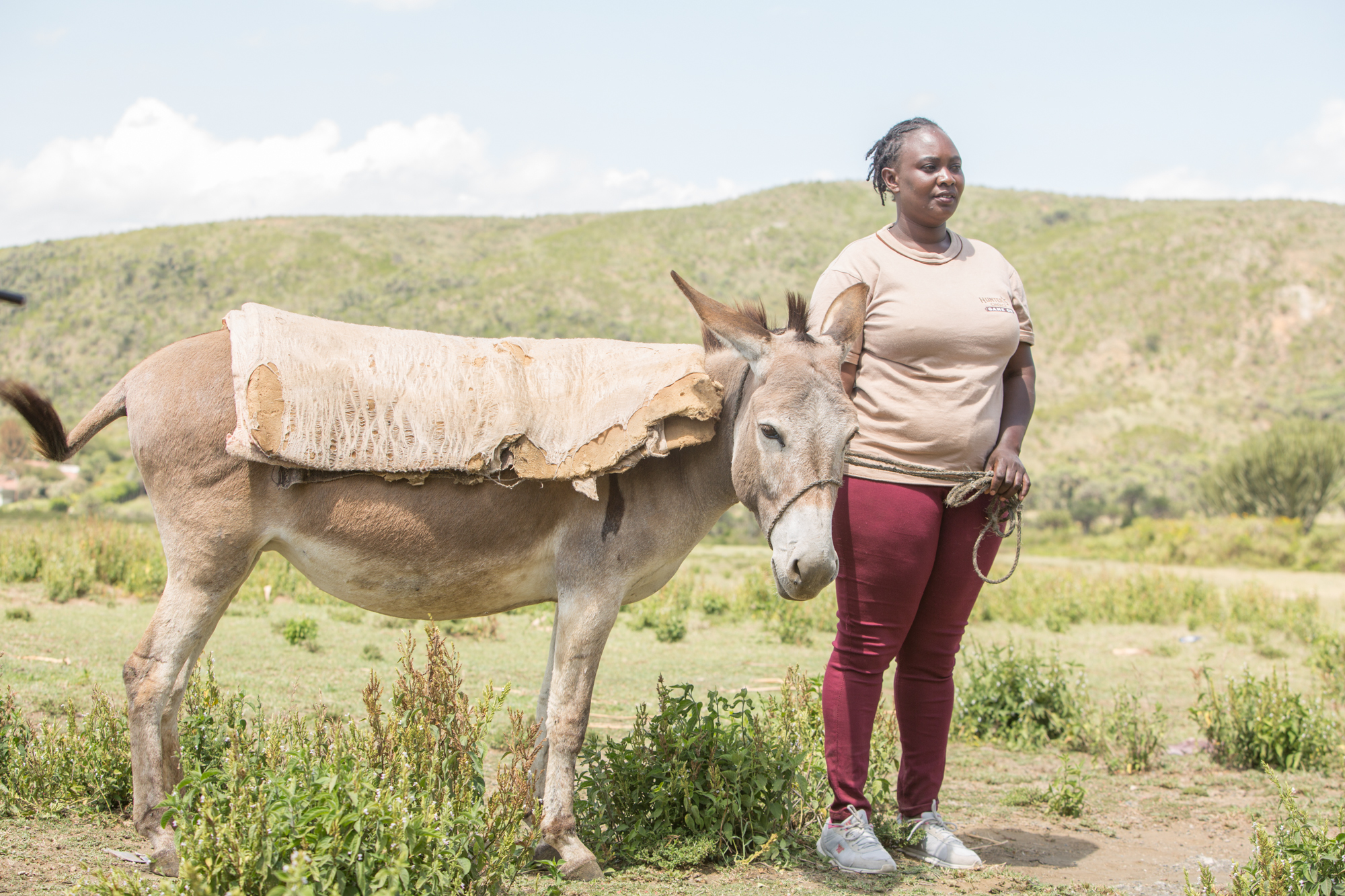 Woman stands with donkey in Kenya