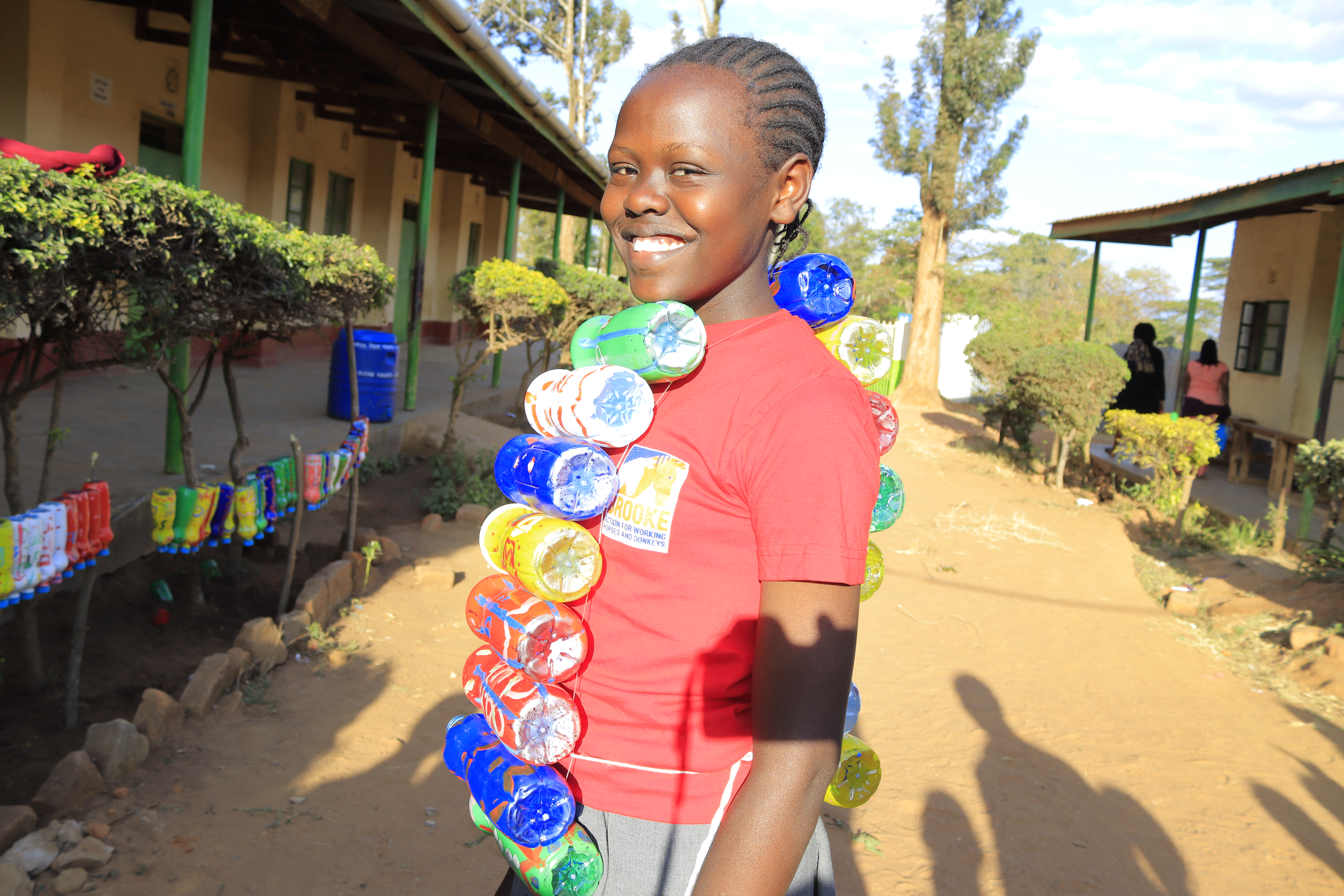 School pupil smiles whilst holding decorated plastic bottles