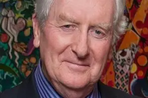 A headshot of David Jones, wearing a blue silk tie and blue striped shirt with black jacket
