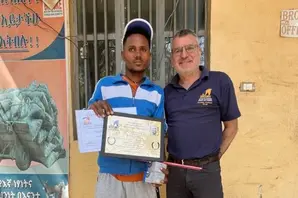 Two men stand together, one holding a certificate