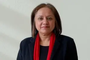 Jasvir wearing a black outfit and a red scarf, standing in front of a white background