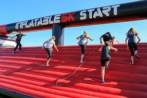 Fundraisers climbing red inflatable obstacle mountain