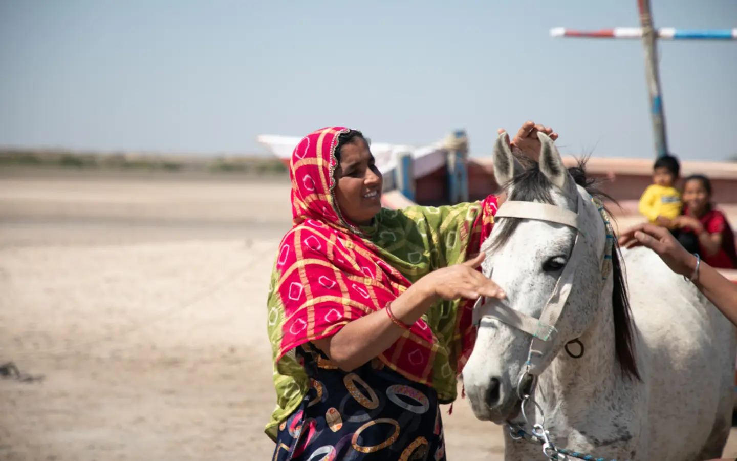 Safura and Varja help a white horse with their harnessing.