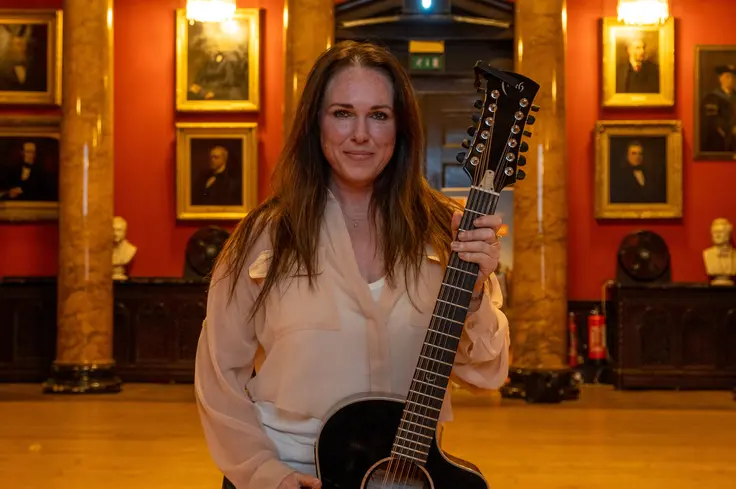 Sandi standing with her guitar