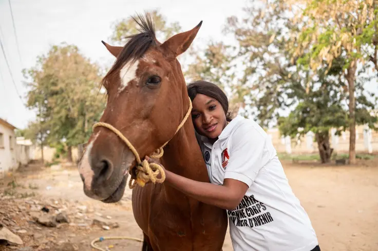 Woman farrier stands with horse